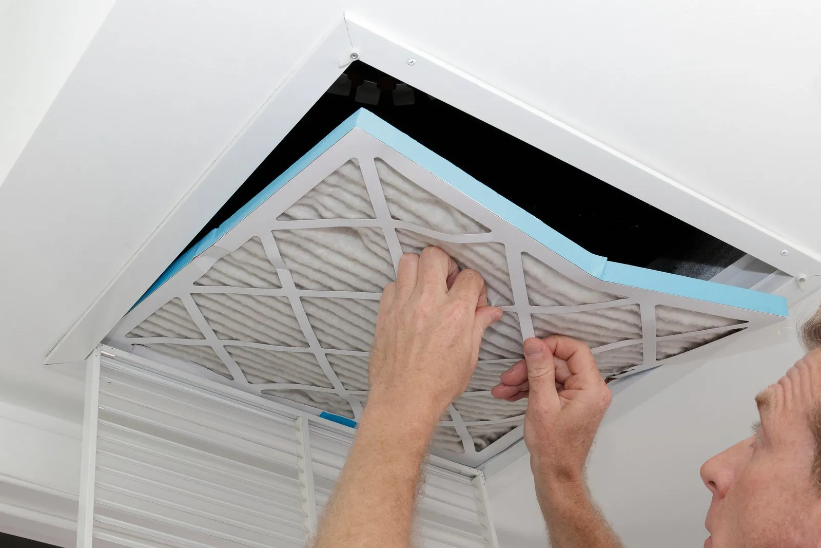 Technician cleaning an air duct vent in a Brighton home